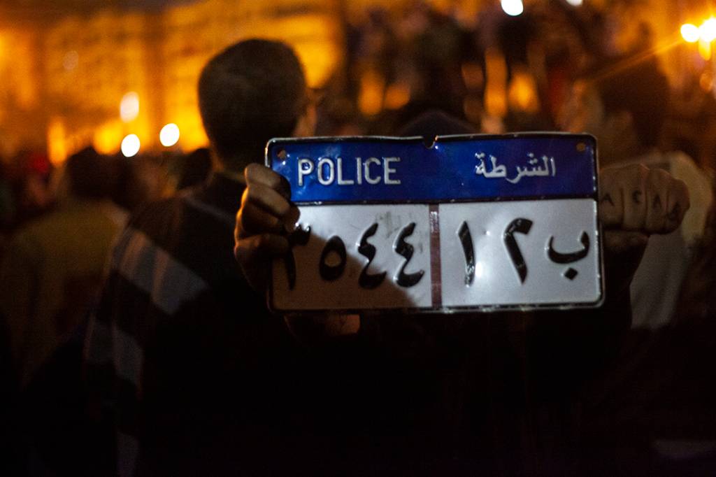 Placa retirada de veículo policial queimado por manifestantes em protesto contra Mohamed Morsi em 28 de janeiro de 2013. Segundo o revolucionário Ahmed Hassan, havia um sentimento de “transbordamento de raiva” nos manifestantes da Praça Tahrir nessa data, que marcava dois anos do começo da Revolução Egípcia. A insatisfação com o presidente se dava porque a Irmandade Muçulmana, grupo religioso que Morsi representava, ‘sequestrou’ a Revolução para chegar ao poder e, no final das contas, aplicaram a sua versão de governo repressivo.