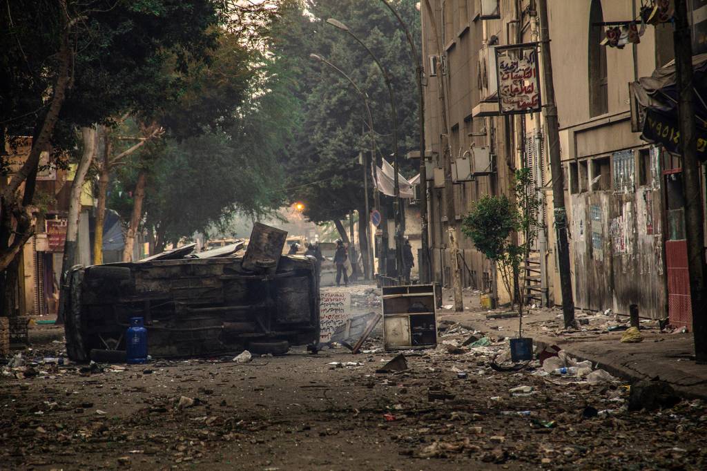 Escombros de um dos embates, ocorrido em 21 de novembro de 2011 na rua Muhammad Mahmoud, do confronto generalizado entre manifestantes e forças policiais que durou seis dias e foi o mais violento após a queda de Mubarak, com mais de 40 vítimas. O confronto se iniciou em 19 de novembro de 2021, após a polícia reprimir violentamente protesto pacífico de famílias no local em memória dos mortos da Revolução Egípcia de janeiro e fevereiro daquele ano. A rua e a Praça Tahrir foram o epicentro dos constantes embates entre população e tropas do governo desde o início da revolução.