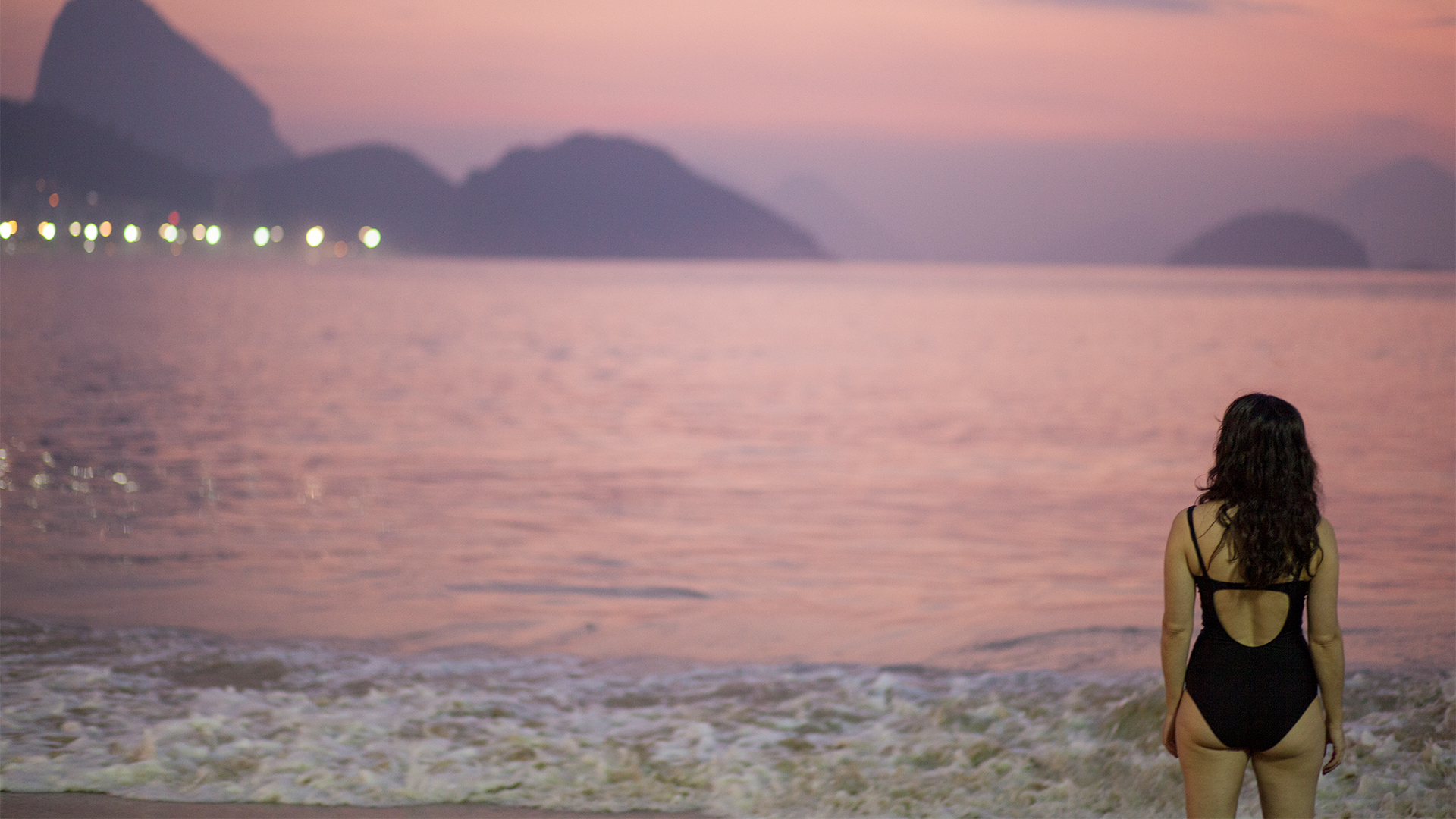 Praia com céu rosa e roxo do fim da tarde.